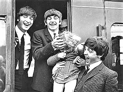 Beatles - John, Ringo and Paul with a young fan as they disembark from the train
