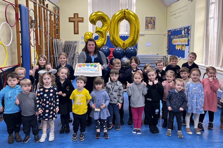 Teddy Bears Pre-school leader Kirsty Cornish with some of the children and a cake to celebrate her 30 years of service Old Cleeve