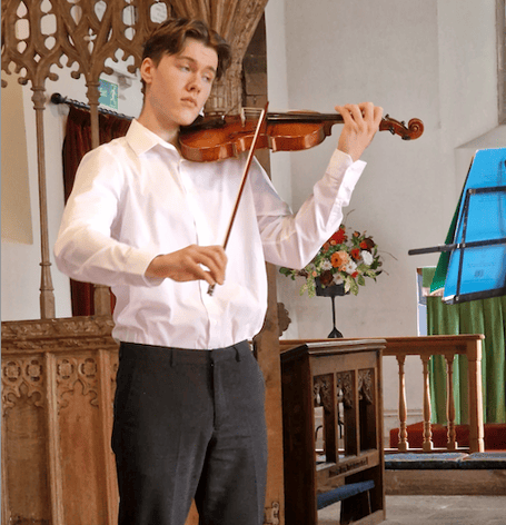 Violinist Anthony Knight performing at a Harvest Festival service in St Petrock's Church, Timberscombe.