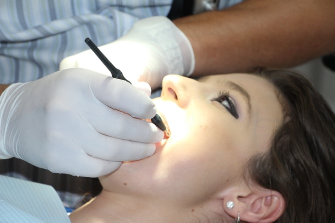 A dental hygienist cleans a patient's teeth.