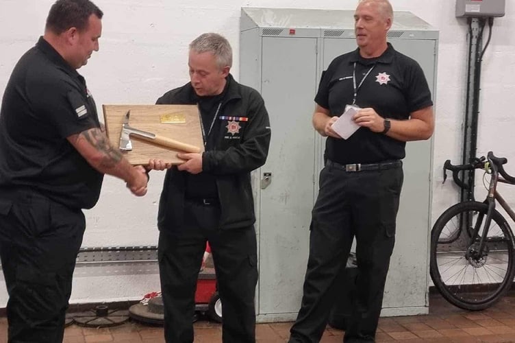 Nether Stowey fireman Richard Nurton (centre) who has retired after 30 years, receives a mounted fire crew axe.