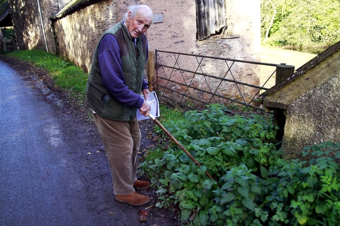 Nicholas Bucknall uses his walking stick to try to clear mud from a drain outside his Brompton Ralph home.