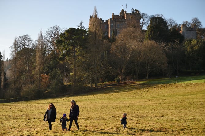 Visitors walking in the parkland in winter at Dunster Castle, Somerset