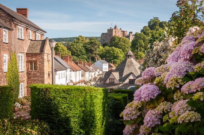 A sunny day in the Exmoor village of Dunster with ancient buildings and blooming flowers