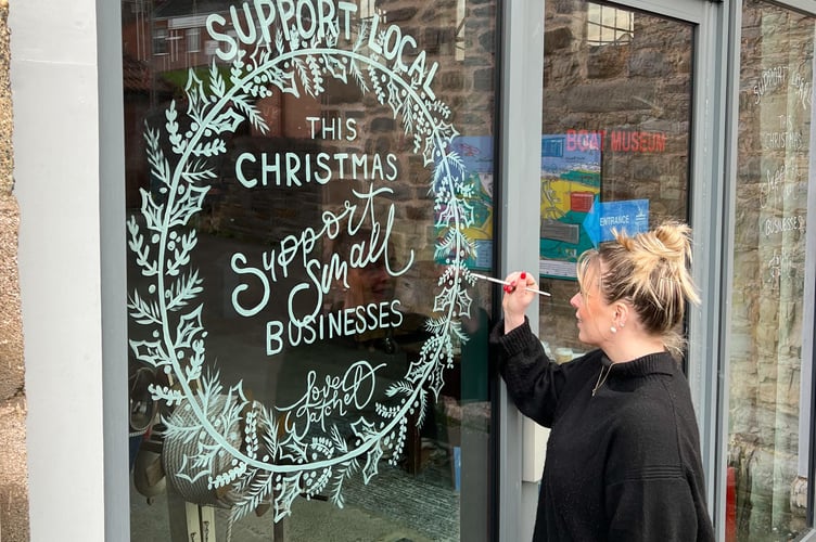 Courtney Davey, of Peppermint Grove Prints, paints the message on Watchet Boat Museum's window.