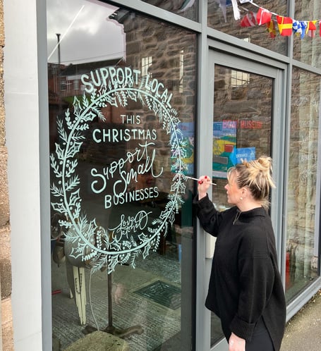 Courtney Davey, of Peppermint Grove Prints, paints the message on Watchet Boat Museum's window.
