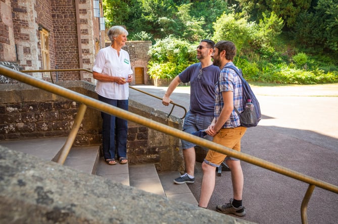 A National Trust volunteer welcomes visitors at the entrance to Dunster Castle.