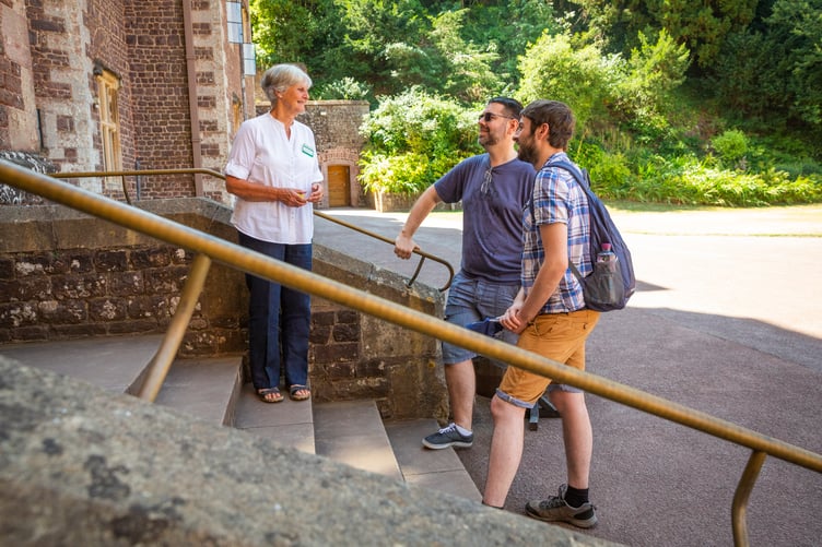 A National Trust volunteer welcomes visitors at the entrance to Dunster Castle.