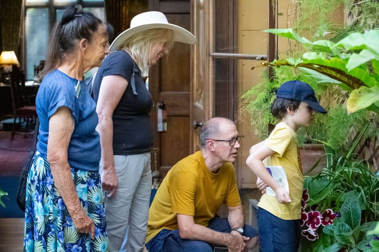 A National Trust volunteer talks with visitors in the conservatory of Dunster Castle.
