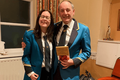 Pete Owen receiving his award from West Somerset Brass Band chairman Jodie Watson to mark 60 years as a member.