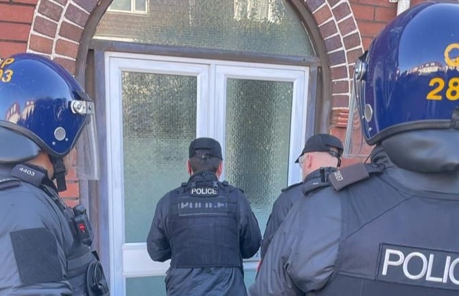Police officers prepare to enter premises suspected to house a large cannabis grow 