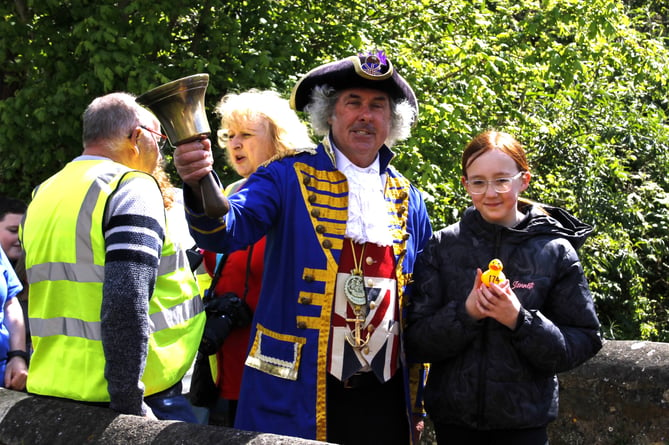 Watchet town crier David Milton prepares to ring the bell as Aleigha Smith holds her duck.