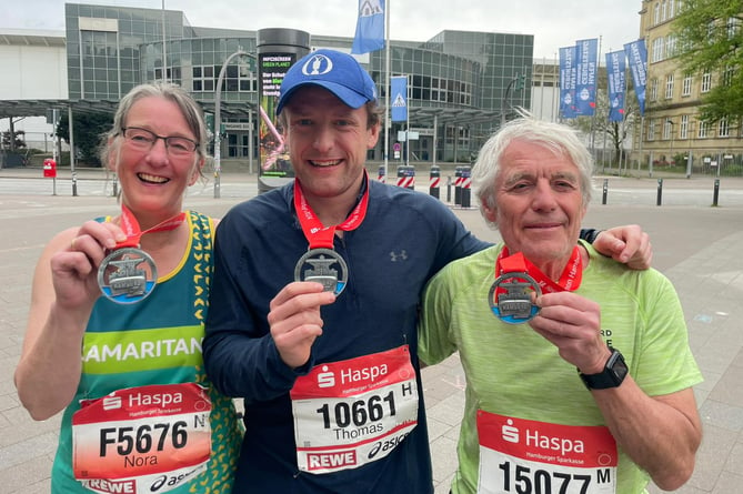 Porlock runner Nora Maw and husband Richard and son Thomas show off theirHamburg, Germany, marathon medals.