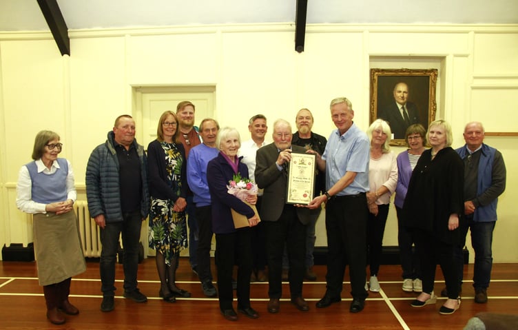 Tim Webb (centre) receives the 'Freedom of the Parish' from Old Cleeve Parish Council chairman Cllr Ian Duncan with his wife Jeanne beside him. Other councillors also attending were Geoffrey Williams, Di Binding, Rick Gaskin, Louise Baker, Matt Ensor, Margaret Smith, Steve Eggar, Chris Dutton, Phil Gannon, and Heather Beaver.
