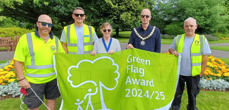 Minehead Mayor Cllr Craig Palmer and deputy mayor Cllr Anne Lawson with amenities staff and the Green Flag awarded to the town's Blenheim Gardens.