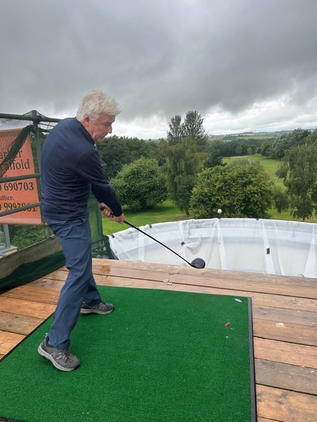Captain Charles St George tees off from his house behind the 12th hole!