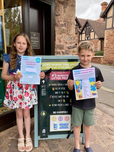 Two visiting children collect their single-use plastic scavenger hunt forms from the National Park Centre, in Dunster.