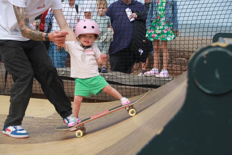 Sixteen-month-old Hazel Drysdale tries skateboarding at Minehead Bay Festival.