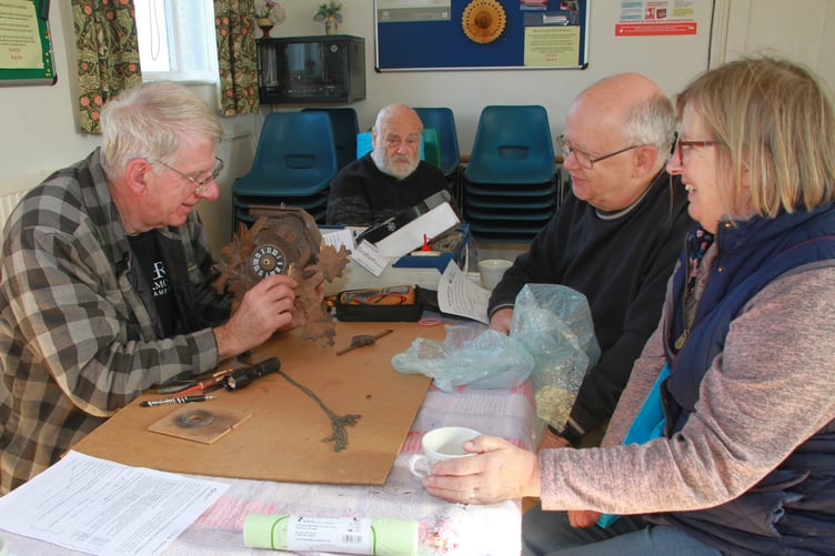 Graham Haw fixes a cuckoo clock for Clive and Christine Longhurst at the first Minehead Repair Cafe. PHOTO: George Ody.