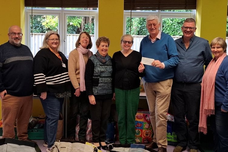 Joyce Merchant and Sandra Wilson, of Dulverton Good neighbours, present a cheque to Moorland Food bank chairman John Preston, watched by Ian Matthews, Roz Matthews, Allison Crisp, Hugh Forster, and Cllr Frances Nicholson.