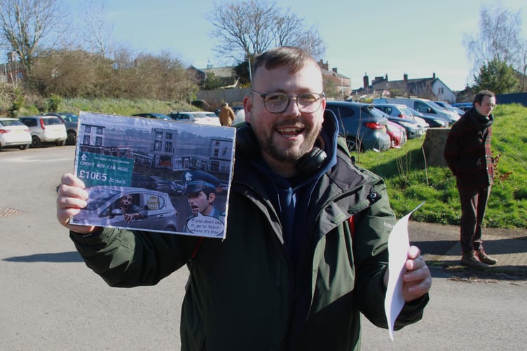 Wiveliscombe resident Dan Bond with a humorous placard against car parking charges. PHOTO: George Ody.