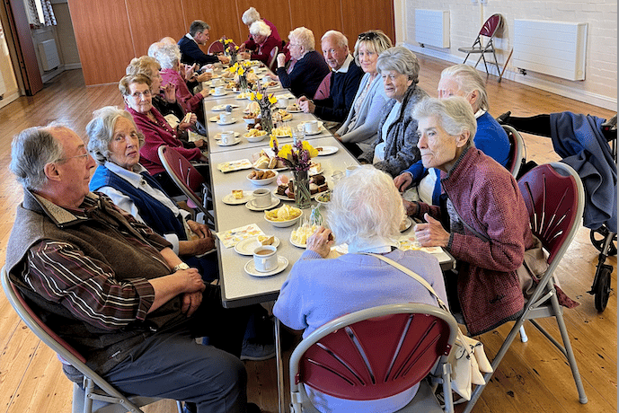 Re-engage charity guests enjoying a tea party in the Moorland Hall, Wheddon Cross.