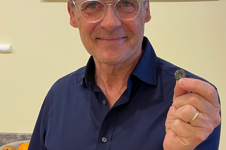 Peter Parminter holds a button which had been lost in Dulverton by his great-grandfather more than a century ago. PHOTO: DWLC.