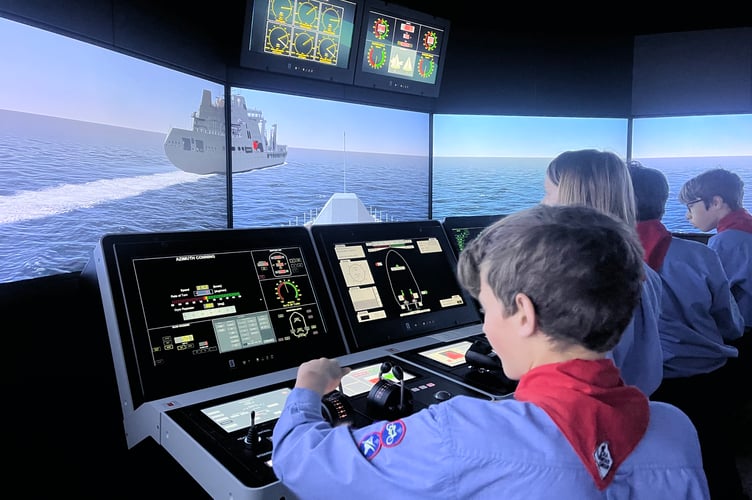 Watchet sea scouts experienced taking the helm of a warship in a bridge simulator during a visit to the Britannia Royal Naval College.
