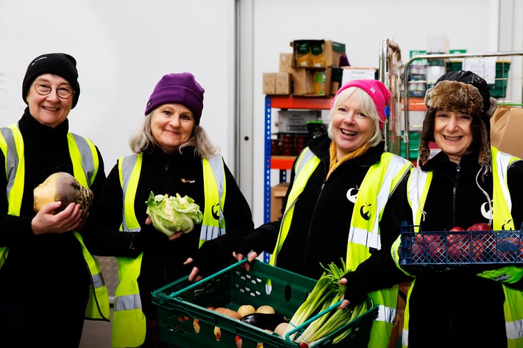 Four volunteer helpers packing fresh vegetables in a FareShare warehouse