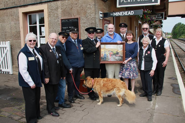 Artist Tim Wetherell and his wife Asia hold a painting presented to Williton Station surrounded by West Somerset Railway staff and volunteers, including Harry Botfield and his dog Max. PHOTO: George Ody.