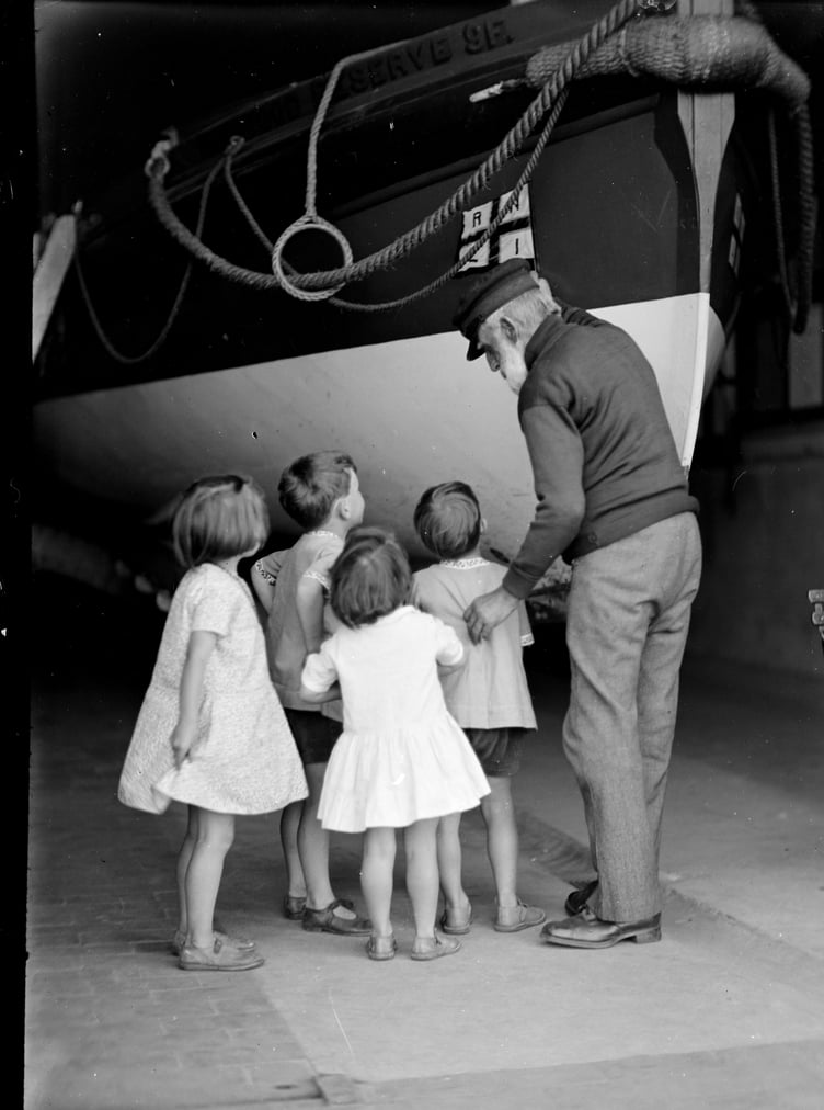 An Ernest Kille print of children being shown Minehead's RNLI lifeboat.