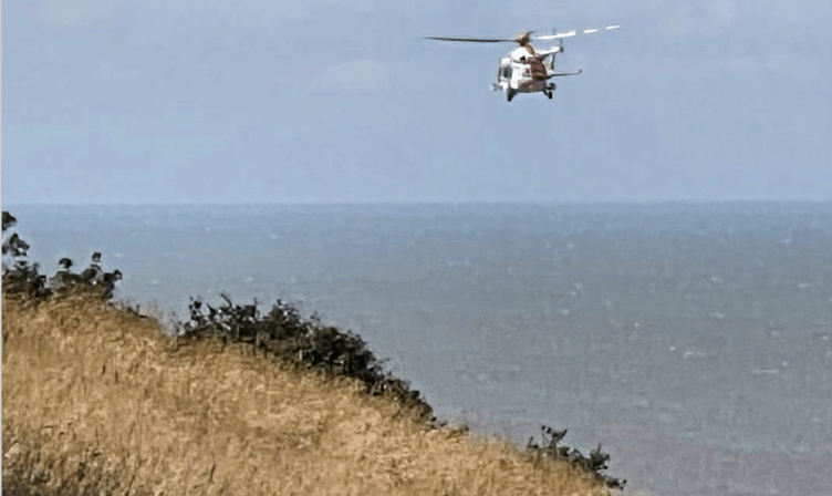 A Coastguard search and  rescue helicopter arrives to winch a stranded coast path walker to safety on North Hill, Minehead. PHOTO: HM Coastguard.