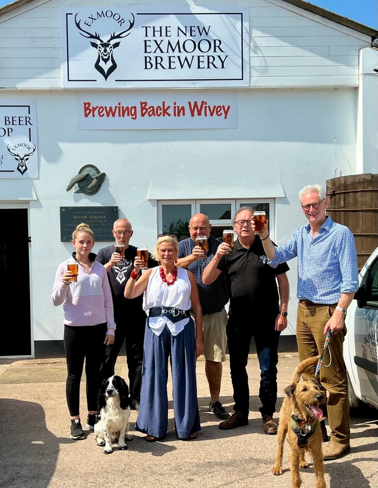The New Exmoor Brewery team (left to right) Taiya Burgess with her dog Ace, Allan Bryant, Shaun Vockins, Jonathan Price, and Rupert Thompson with his dog Basil, raise a celebratory glass with local MP Rachel Gilmour (front).