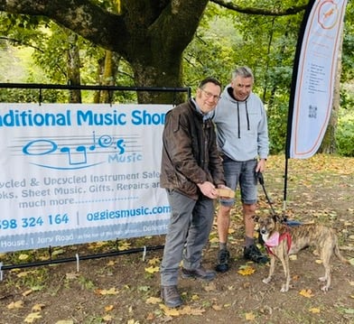 The winning canicross dog, Luna, owned by Phil Thorne (right), receives a bone-shaped box filled with treats from Pet Pain Relief sponsor, Dr James Hunt