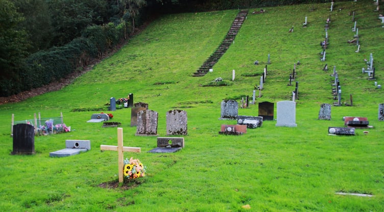 The grave in Porlock Cemetery of Richard Growden's mother, marked by a wooden cross, is surrounded by burial plots with headstones which have been flattened. PHOTO: George Ody.