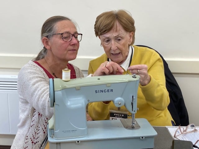Eileen Hill shows how to re-thread a sewing machine brought in for repair at Carhampton Repair Café.