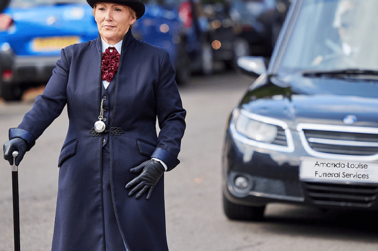 Funeral director Amanda-Louise Knight pacing ahead of a hearse.