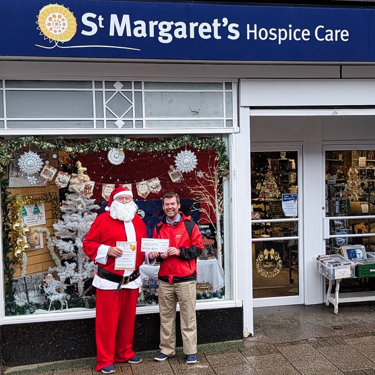 Minehead Rotary Santa presents a £200 cheque to St Margaret’s Hospice local community fund-raiser David Jones at the charity’s shop in Friday Street, Minehead.