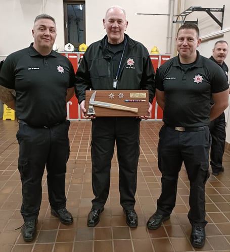 Williton firefighter Ian Hall (centre) receives a mounted fireman's axe and a medal as he retires after 40 years.
