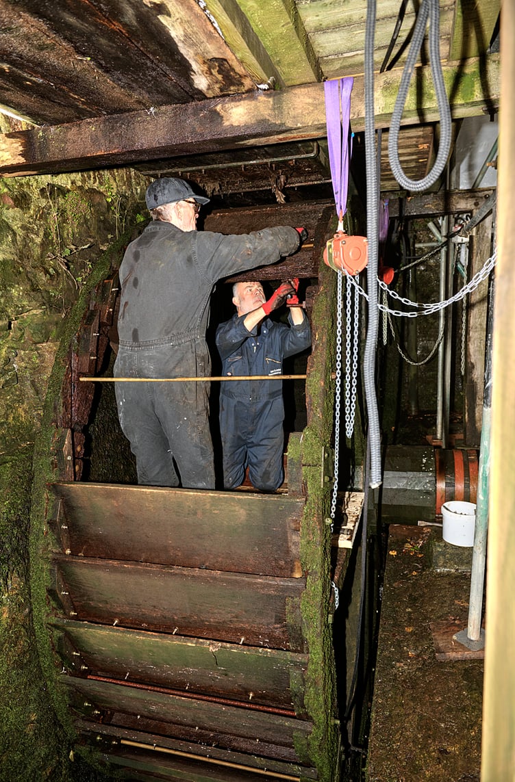 Craftsmen working on the restoration of one of Dunster Watermill's waterwheels.