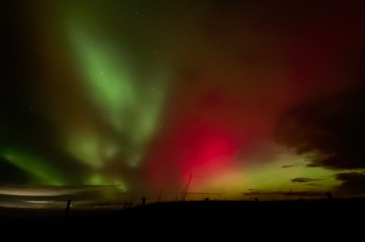 Beams of red and green light illuminate the sky.