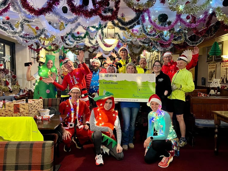 Katrina McGrath, of Calvert Trust Devon, receives a cheque for £1,000 from members of Minehead Running Club.