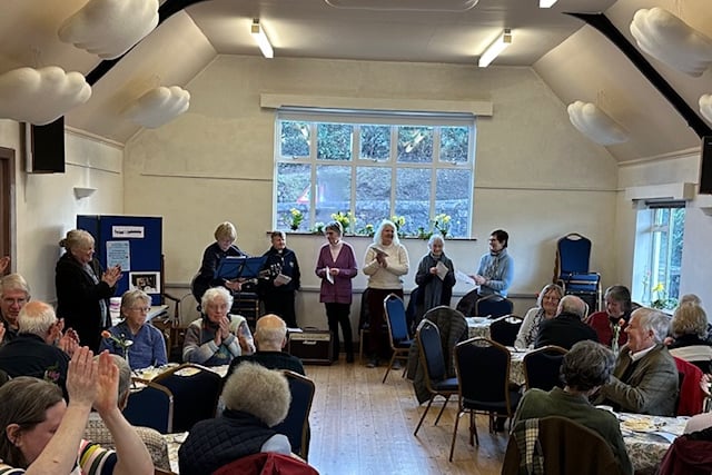 Guests enjoy a 'songs and scones' community afternoon in Porlock Village Hall.