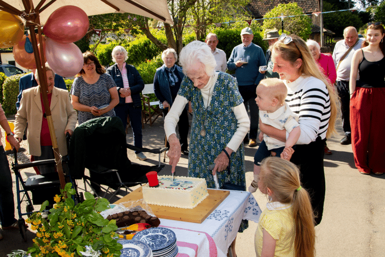 Jane Bunbury, Crowcombe's oldest resident, and youngest villager Henry Hickman, do the cake cutting honours at a 25th birthday party for the community shop and Post Office.