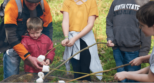 Roasting marshmallows over a fire in the forest school in Lorna Doone Valley, on Exmoor.