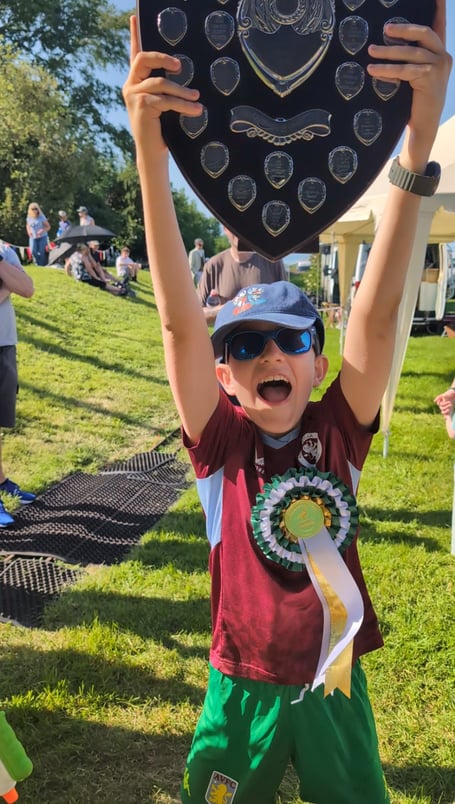Porlock duck race winner Theo Harley with his shield and rosette.
