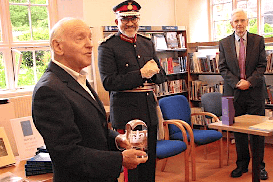 Roger Stacey accepts the King's Award for Voluntary Service crystal trophy from Somerset Lord Lieutenant Mohammed Saddiq on behalf of Thomas Poole Library volunteers in Nether Stowey.