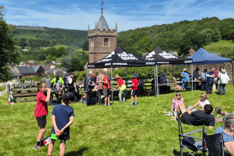 A view of Timberscombe's paternal family fun day and barbecue with St Petrock's Church in the background.