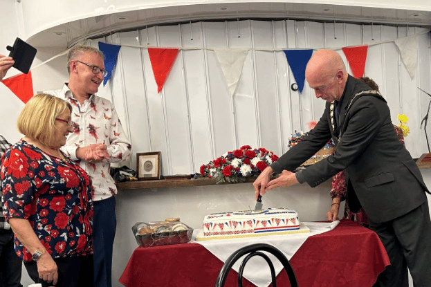 Minehead Mayor Cllr Craig Palmer cuts a 30th anniversary cake to celebrate the town's winning with Saint Berthevin, in France.