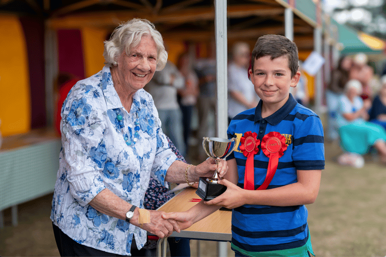 Val Norman presents a trophy in memory of her husband to last year's Watchet Flower Show children's winner Zachary Moore.
